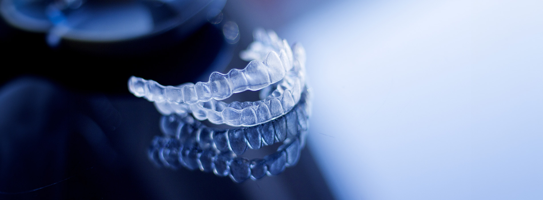 The image shows a close-up view of a transparent object with a complex structure, possibly a piece of equipment or a scientific apparatus, set against a blurred background that appears to be illuminated from below in blue light.