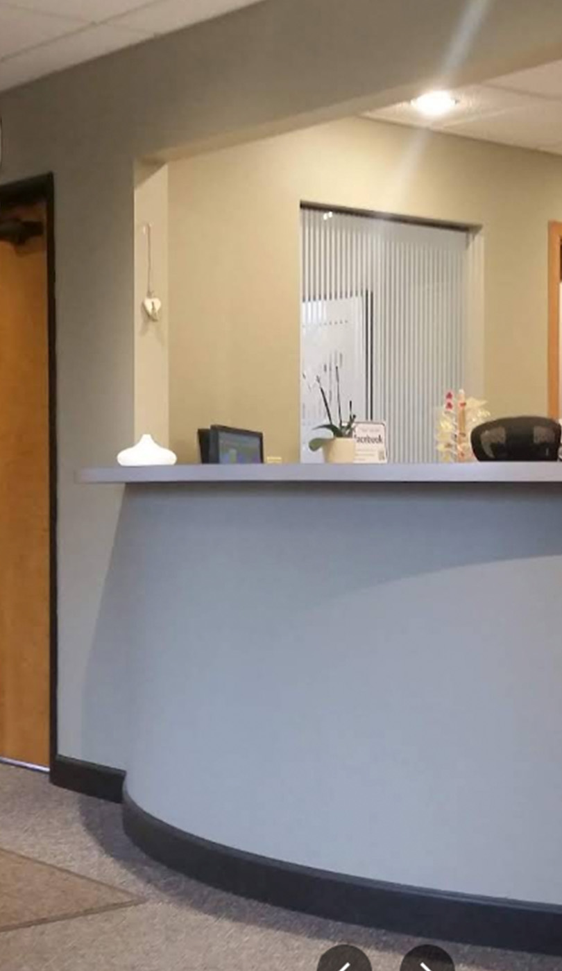 The image shows a modern dental or medical office interior with a dental chair, equipment, and a clean, professional environment.