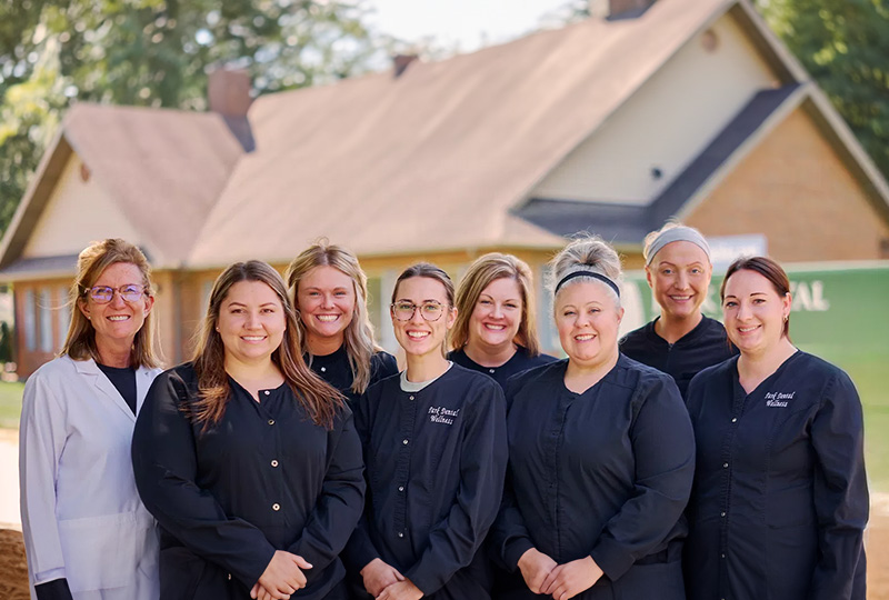 The image shows a group of individuals standing outdoors in front of a building, possibly posing for a photograph. They appear to be professionals dressed in uniforms, which suggest they might be healthcare workers or staff from a professional organization.
