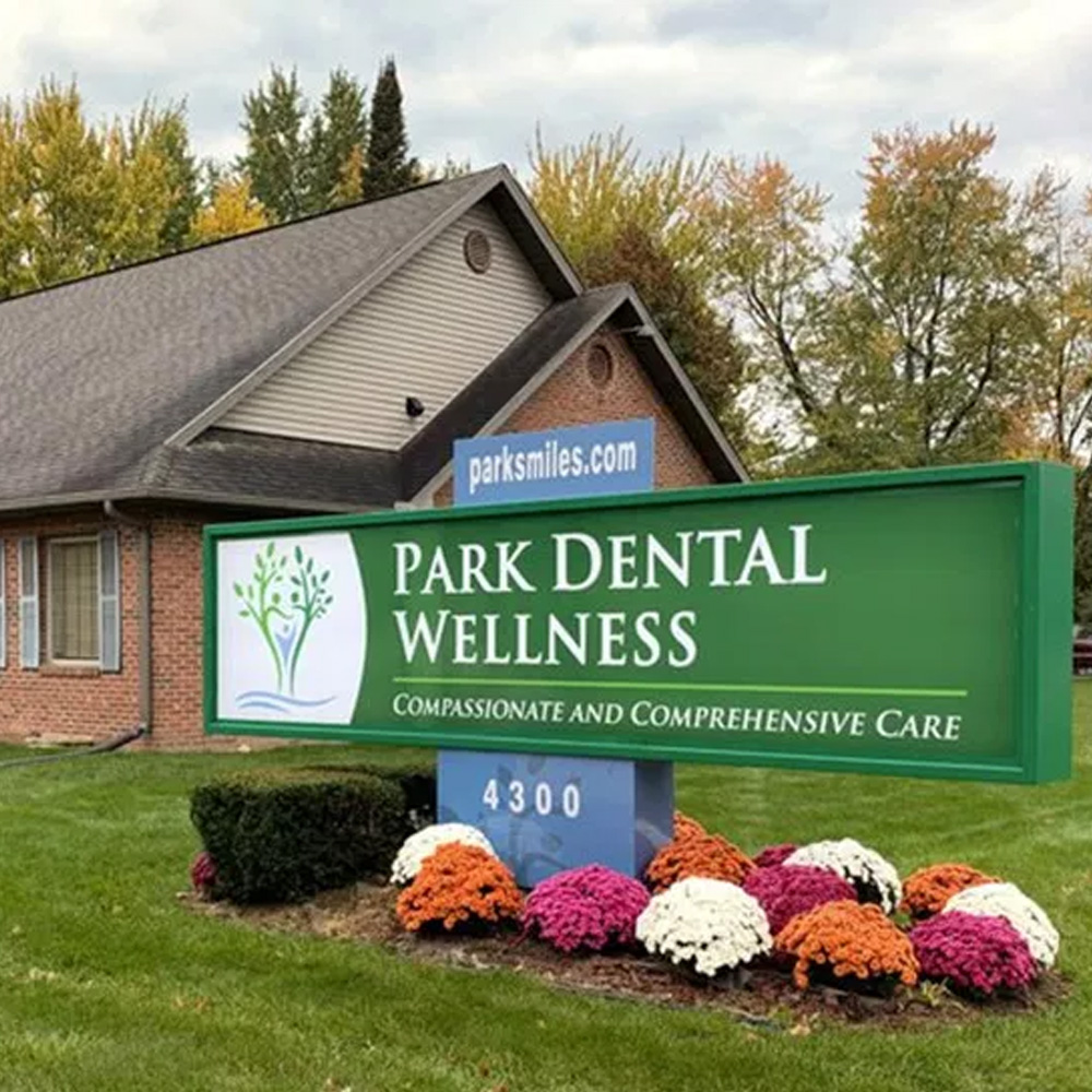 The image shows a sign for  Park Dental Wellness  with a tree graphic and the message  Compassionate and comprehensive care.