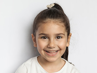 A young child with a big smile, looking directly at the camera.